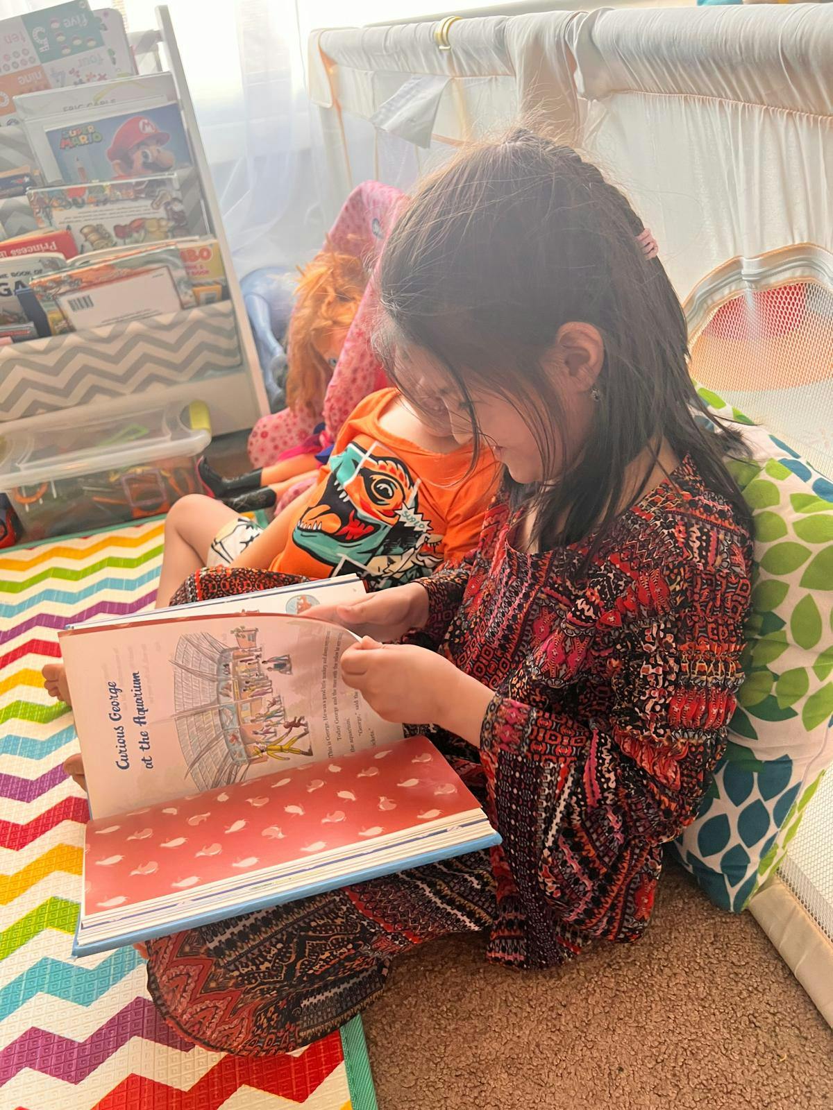 Child reading a book on a colorful rug