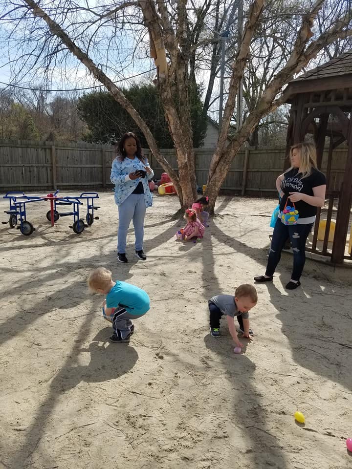 Two adults and two children in a sandy outdoor area