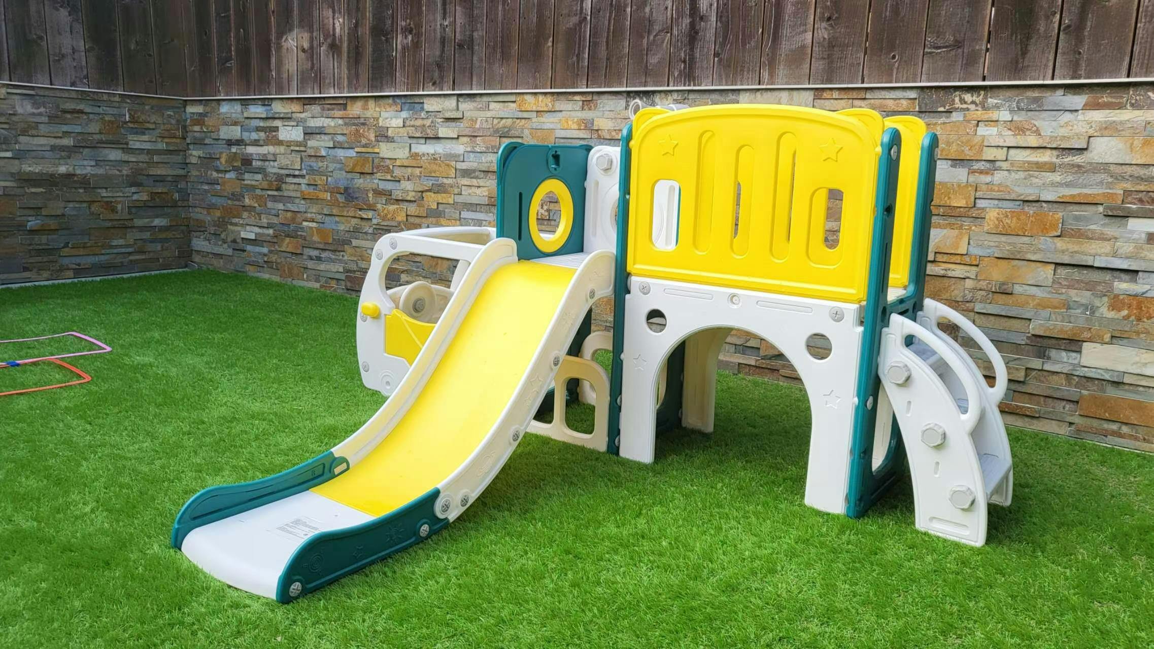 children's outdoor playset with a slide and climbing structure on artificial grass