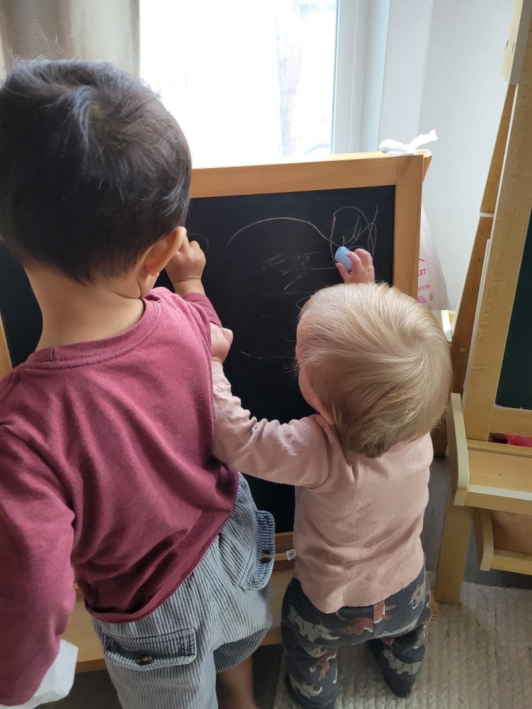Two children drawing on a chalkboard