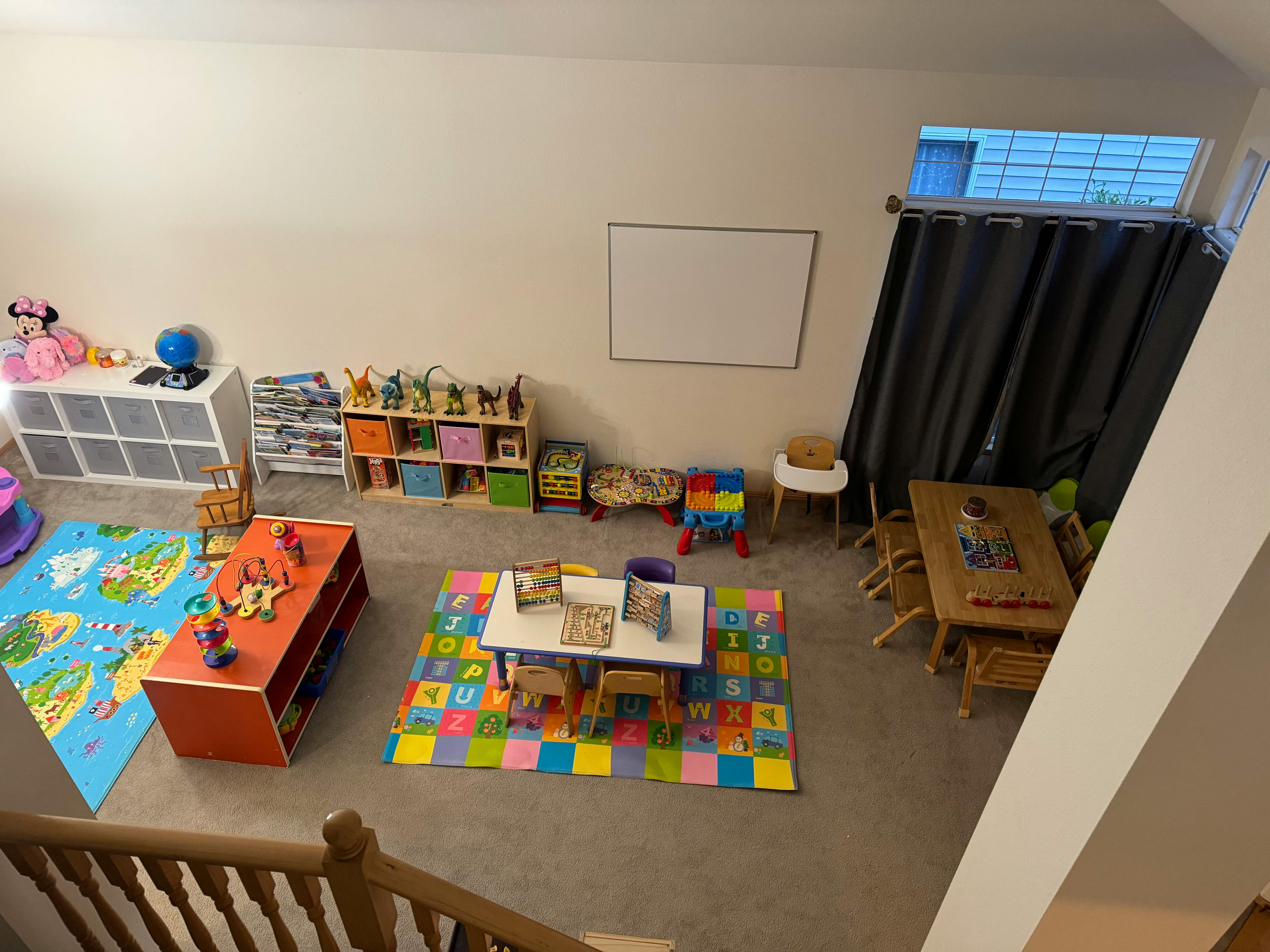Playroom with colorful rugs, small tables, chairs, and shelves with toys