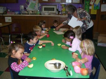Adult and children at a table with apples