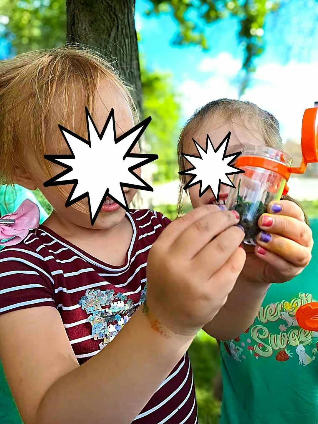 Two children looking at something in a small container