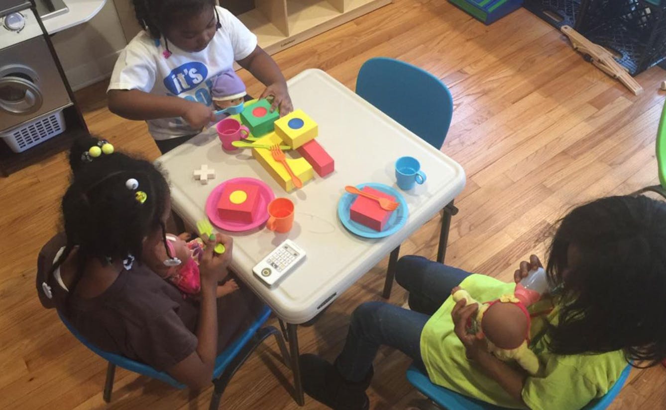 Three children playing with toys at a small table