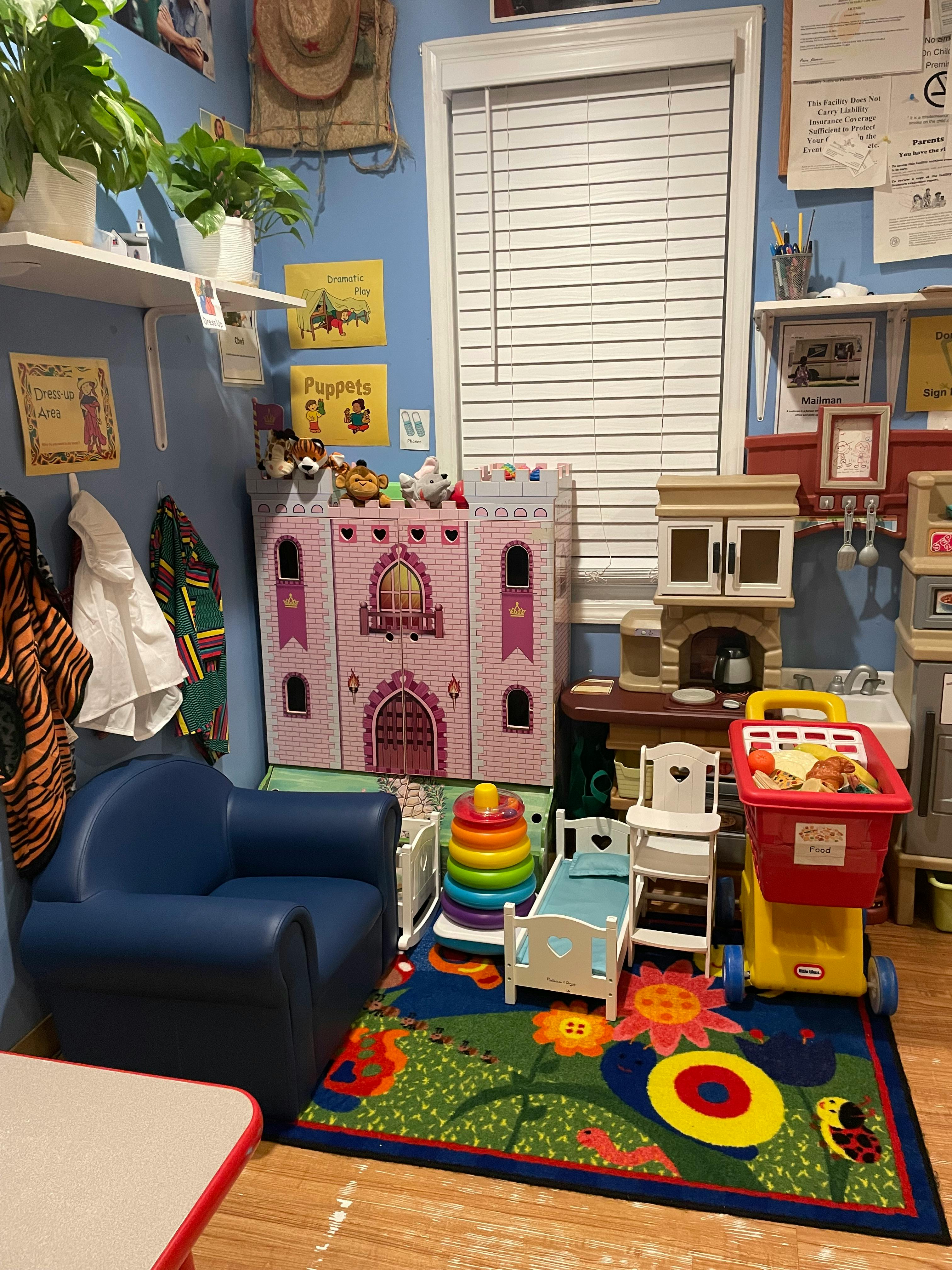 Children's play area with a dollhouse, toy kitchen, and small furniture