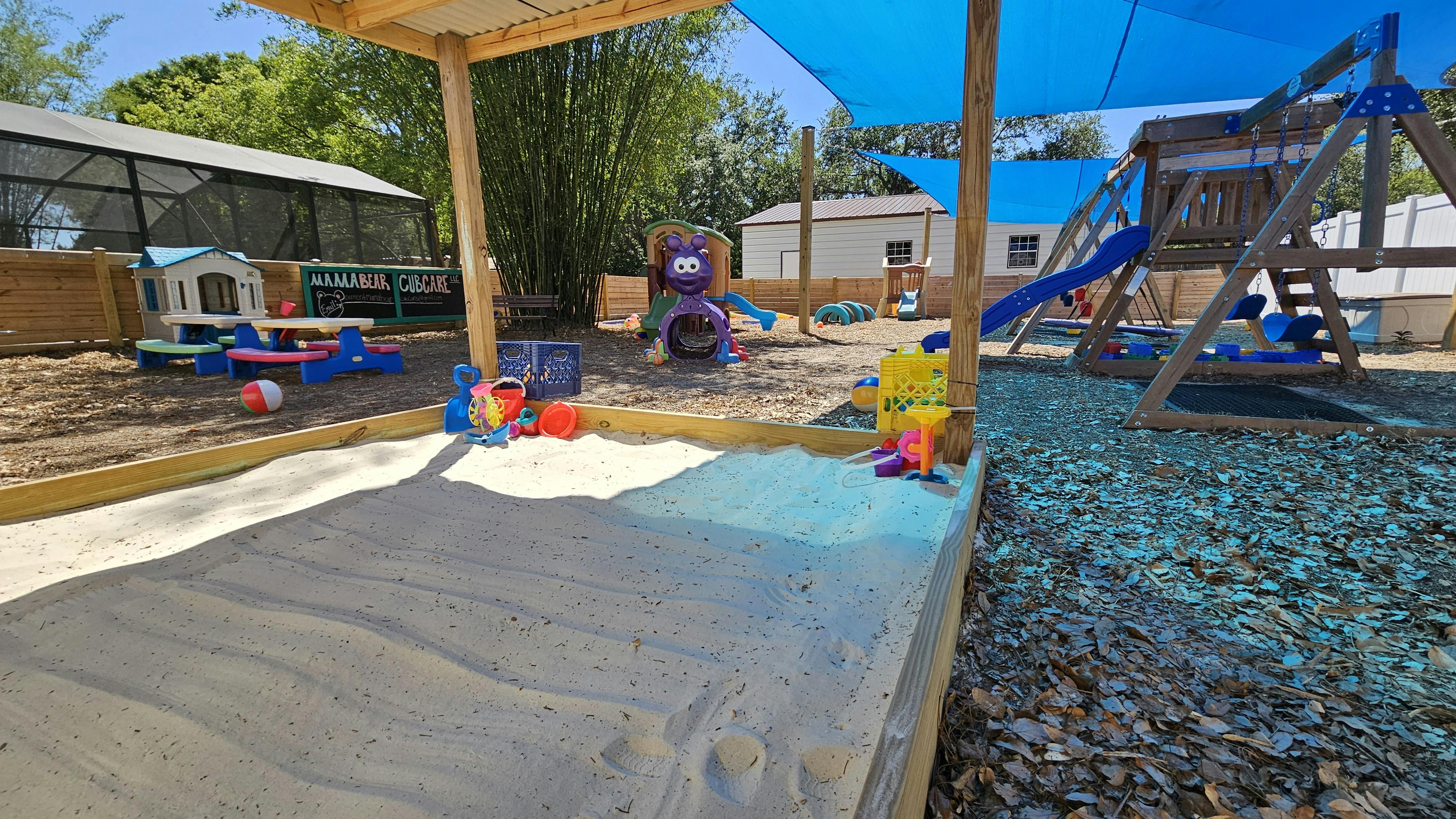Outdoor playground with sandbox, swing set, and play structures