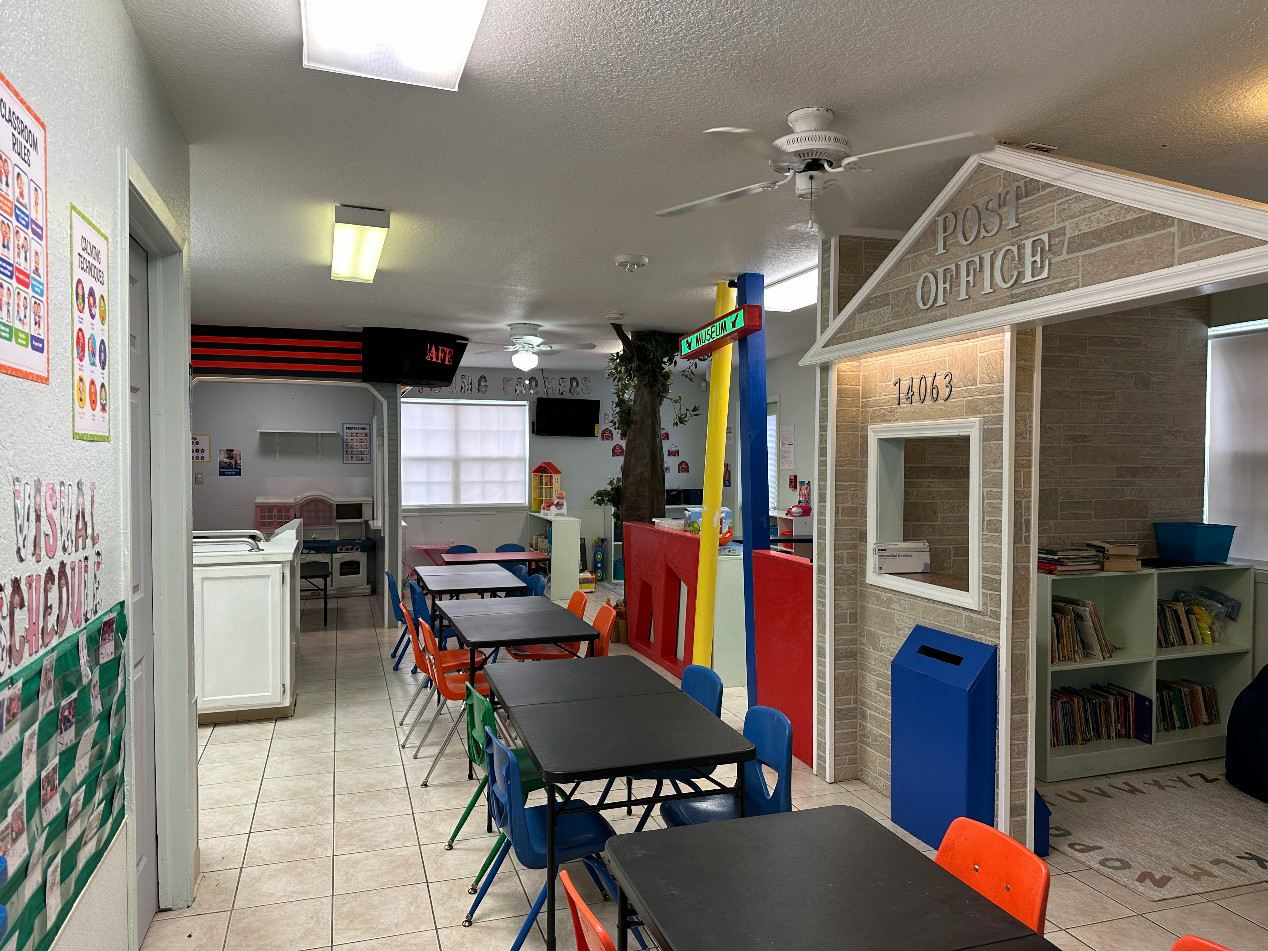 Classroom with small tables and chairs, and a play post office structure