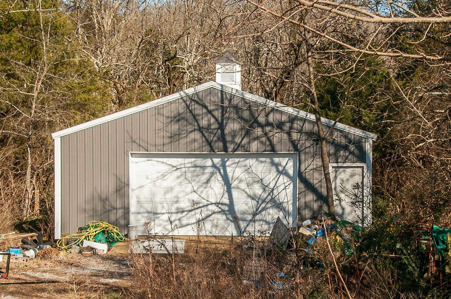 Gray shed with a white garage door and a small white door