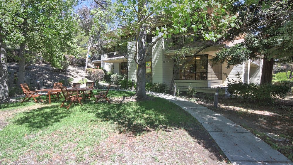 Outdoor patio furniture on grass next to a building with a walkway