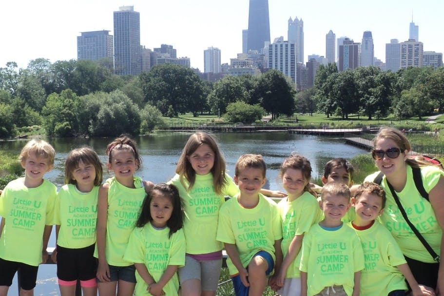 Group of children and an adult in matching shirts in front of a city skyline