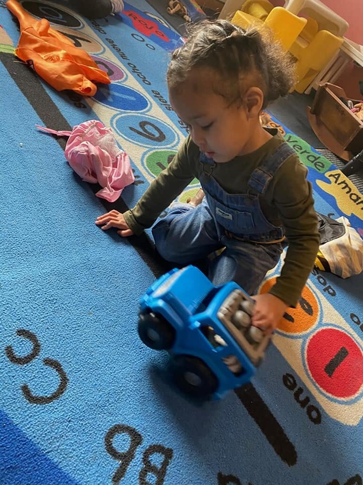 Child playing with a toy truck on a patterned rug
