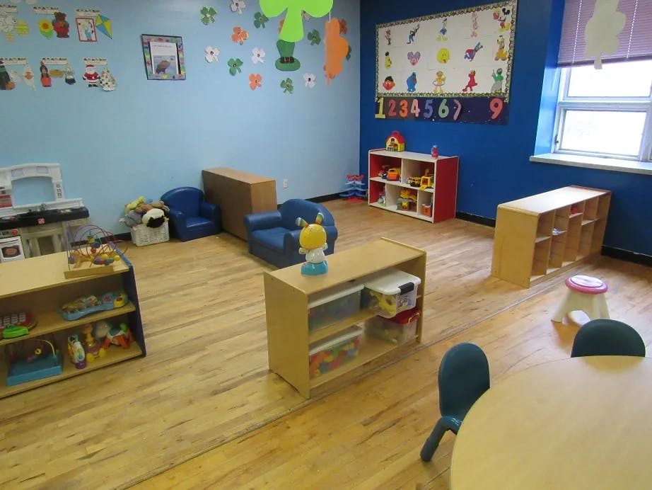 Empty classroom with small chairs, tables, and shelves with toys
