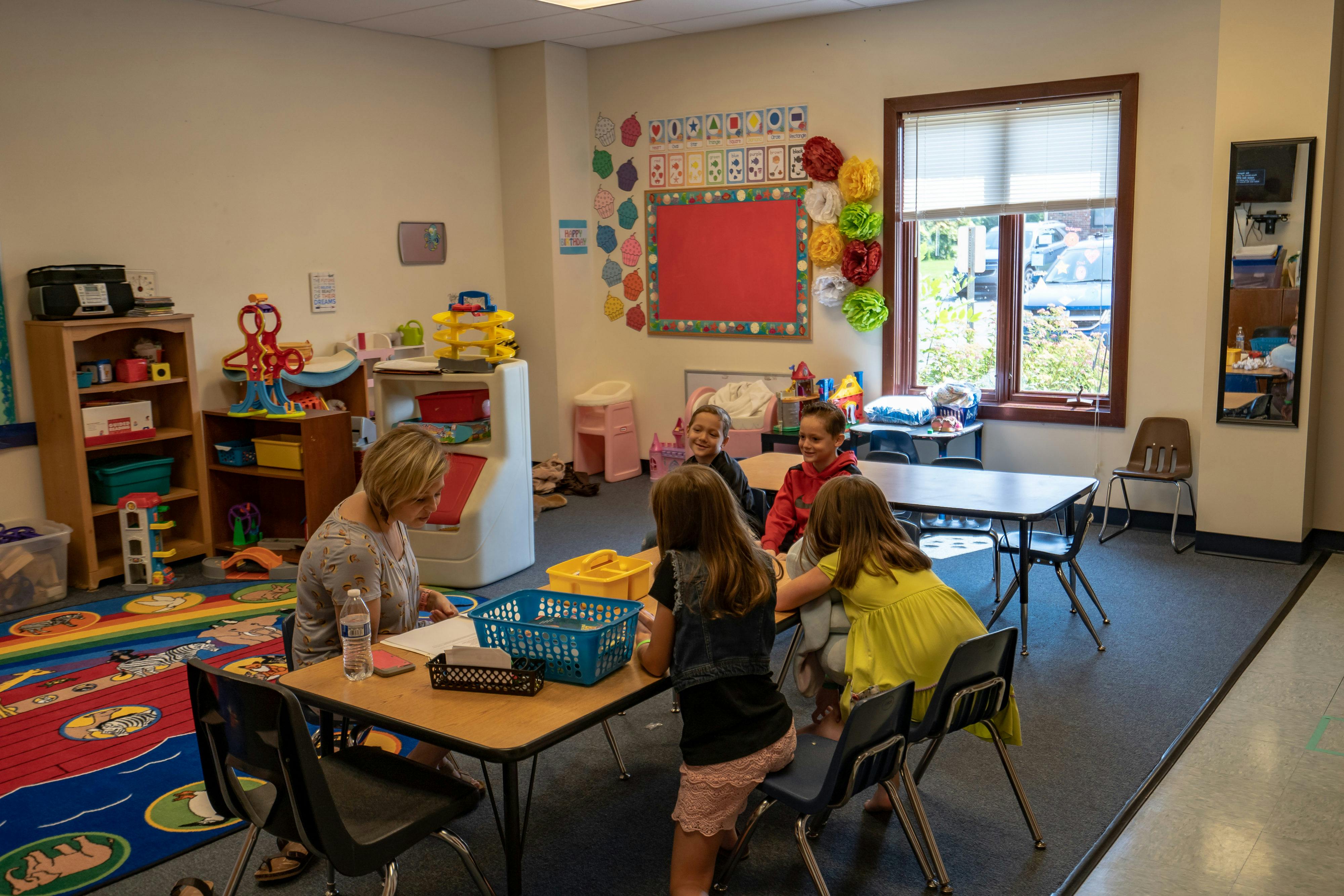 Adult and children at tables in a classroom