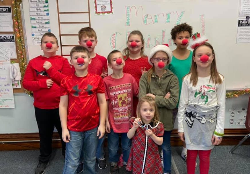 Group of children wearing red clown noses in a classroom