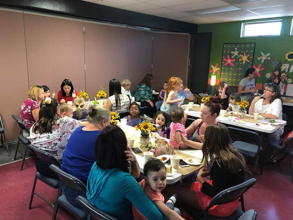 People and children gathered around tables in a room