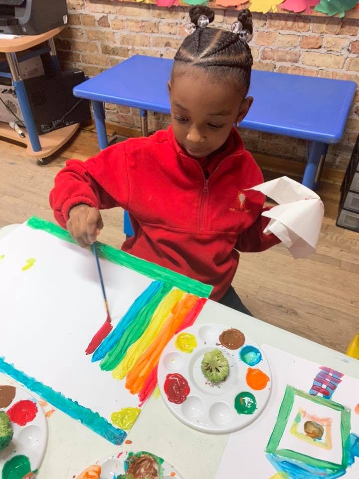 Child painting a rainbow on paper