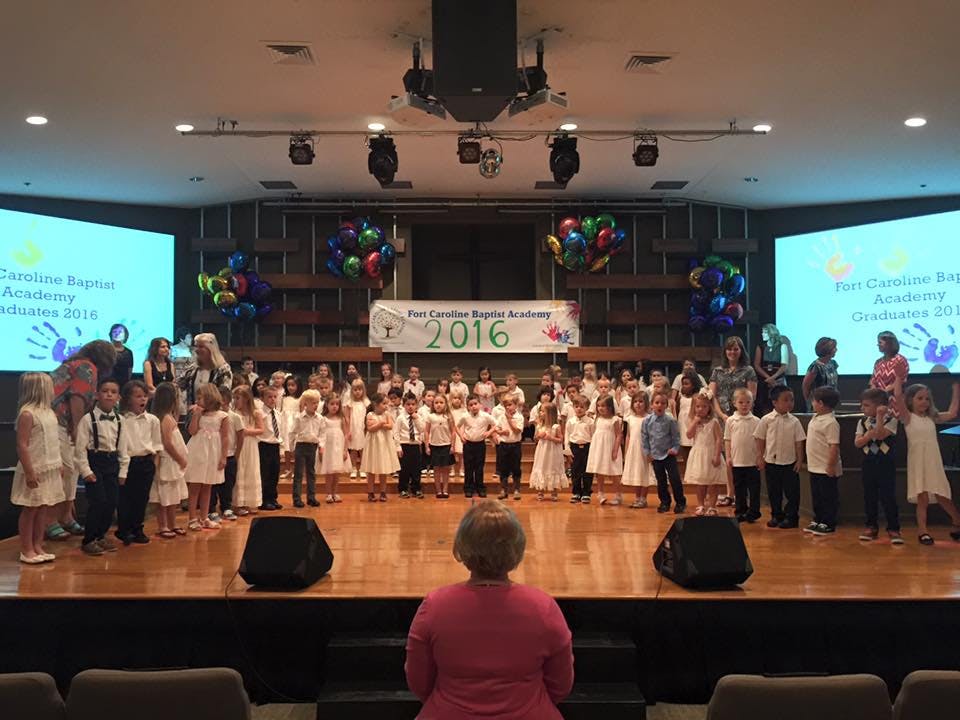 Children on a stage with a banner that reads "2016"