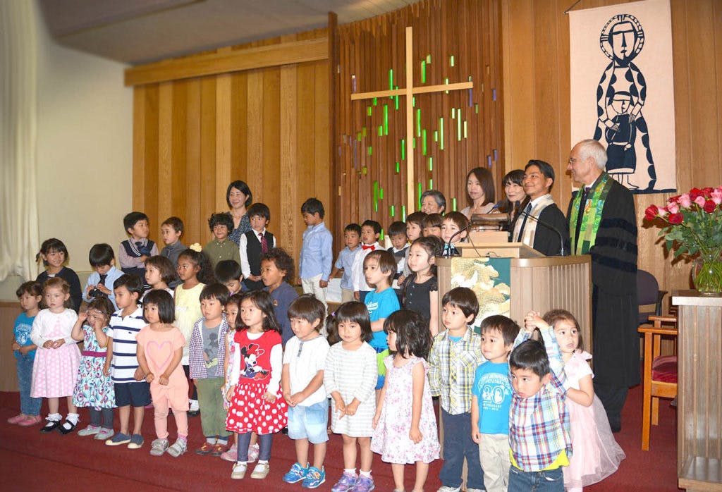 Adults and children standing in front of a wooden cross