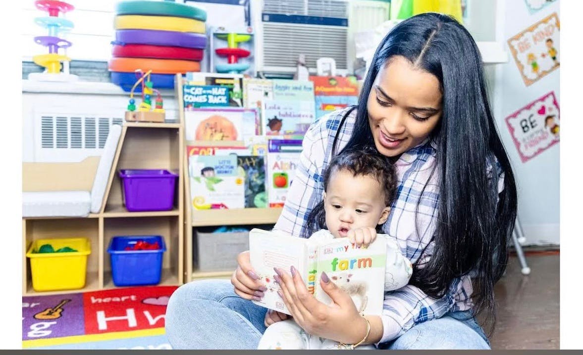 Person holding a child and reading a book in a classroom