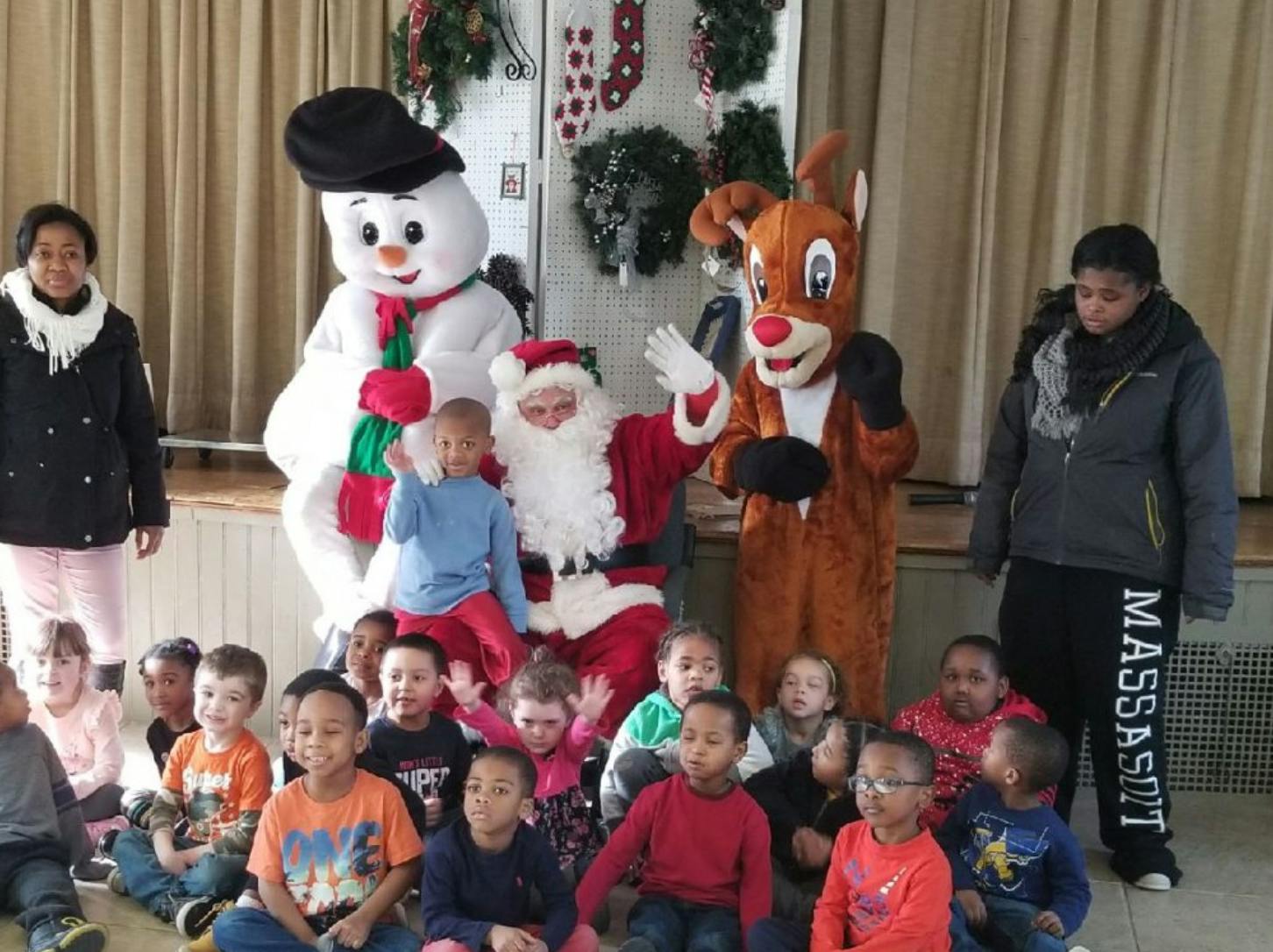 Santa, a snowman, and a reindeer mascot with a group of children
