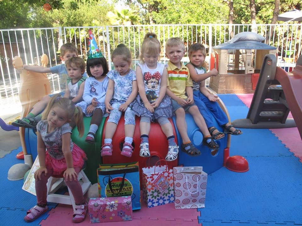 Group of children sitting on playground equipment with gifts