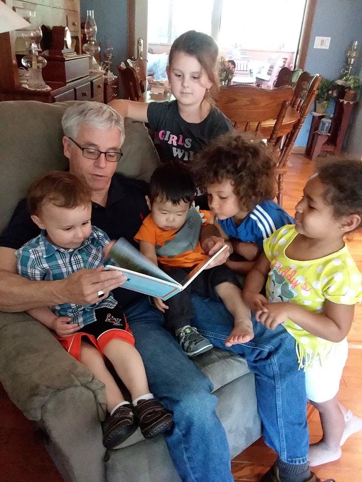 Person reading a book to multiple children on a couch