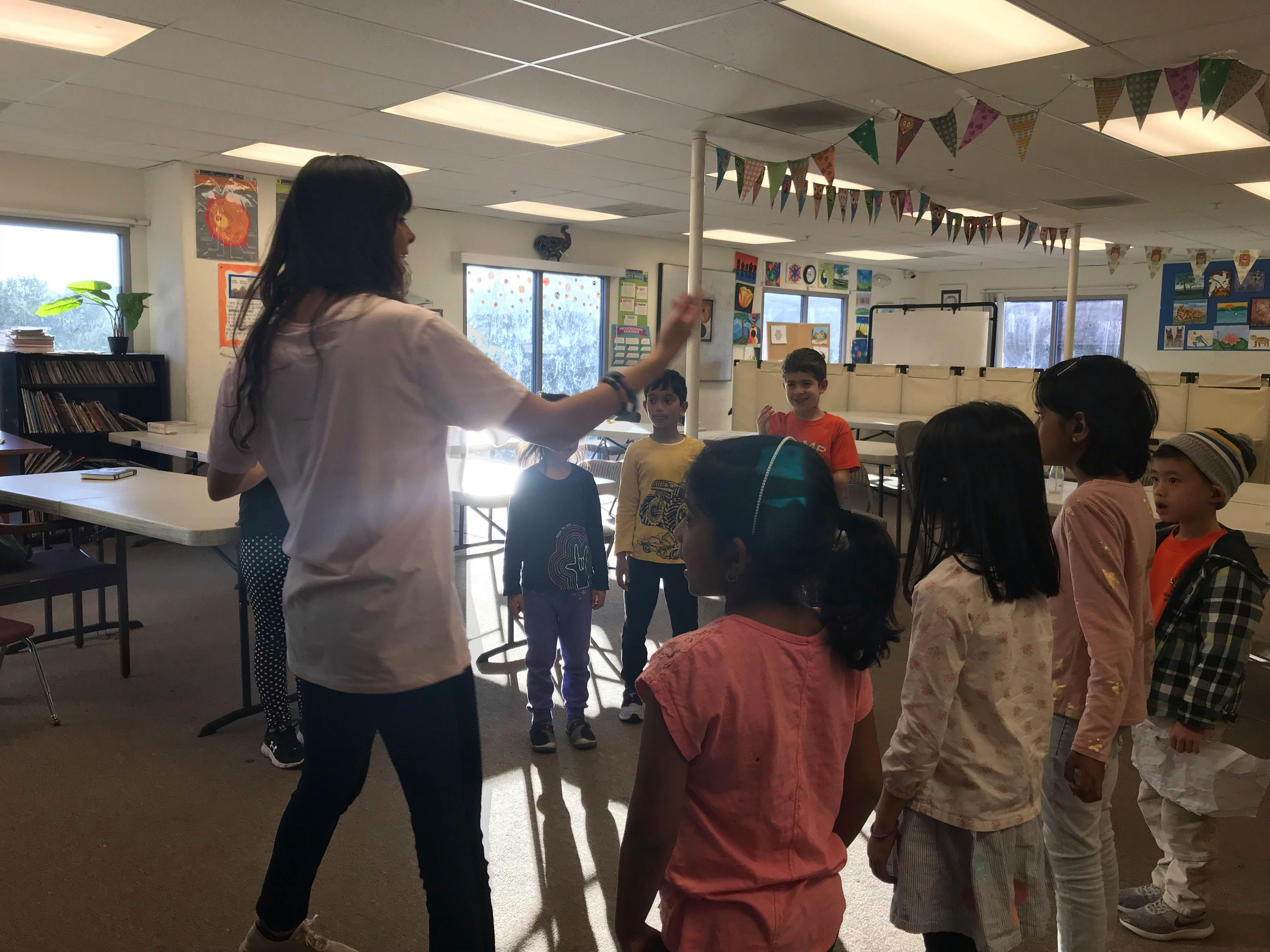 Person leading a group of children in a classroom