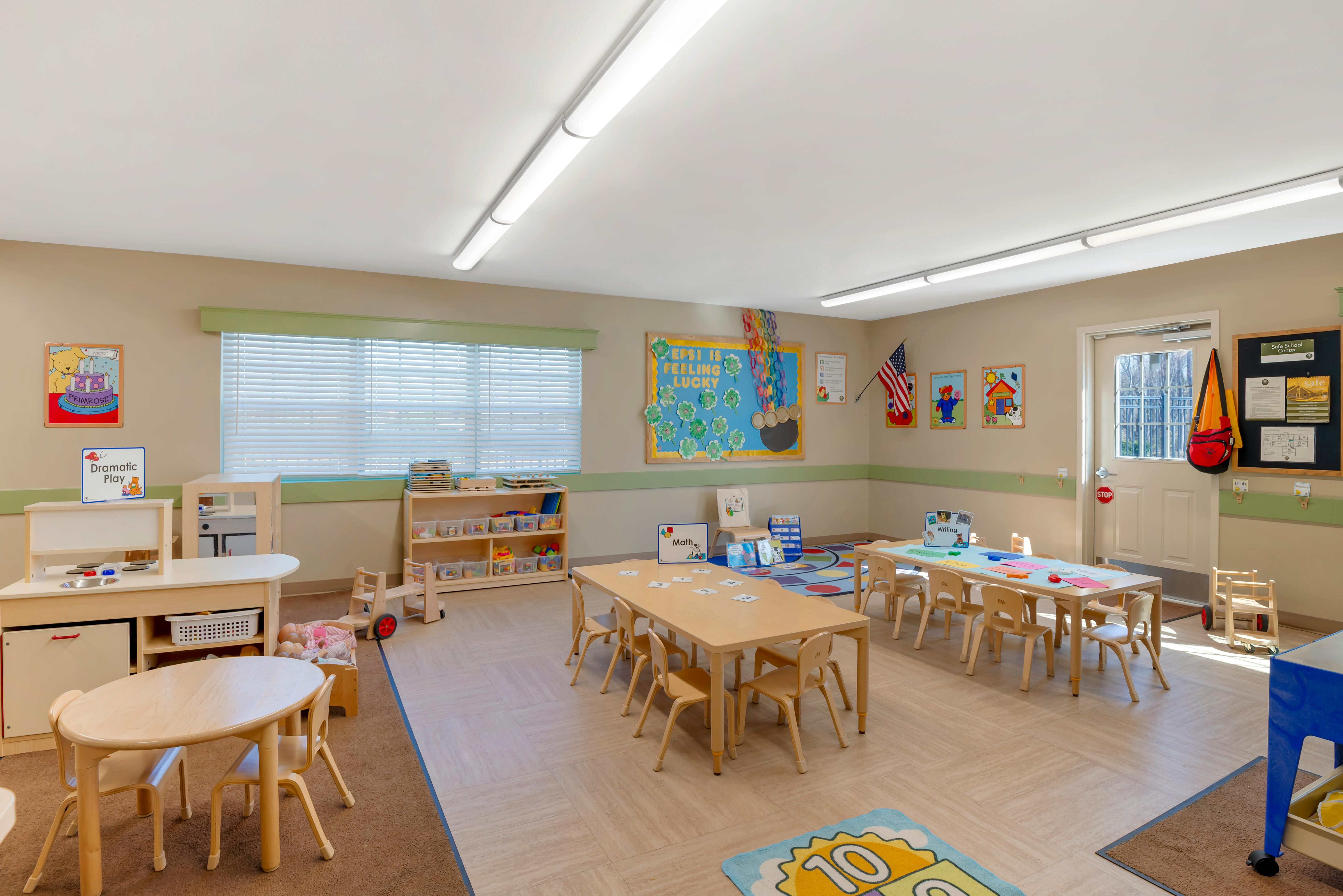 Classroom with child-sized tables and chairs, play kitchen, and colorful wall decorations