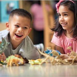 Two children playing with toy dinosaurs