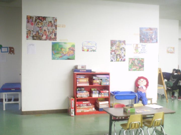 Classroom with a red bookshelf, tables, and artwork on the wall