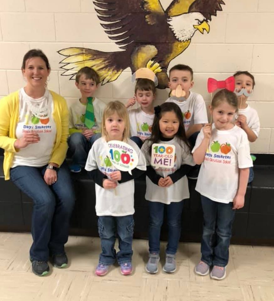 Adult and children posing with signs in front of an eagle mural