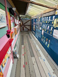 Narrow wooden walkway with displays on walls and along the walls