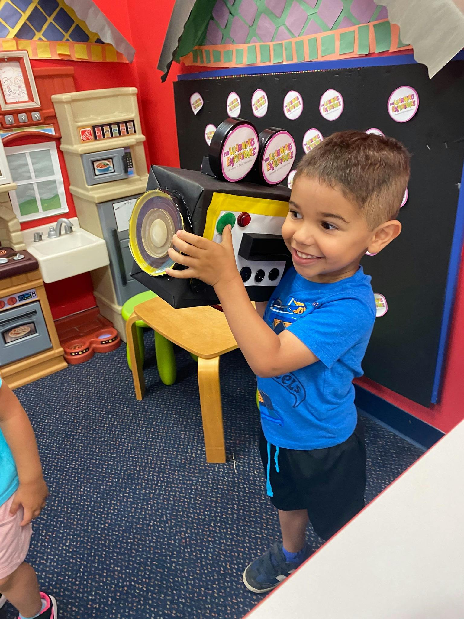 Child playing with a toy camera in a classroom