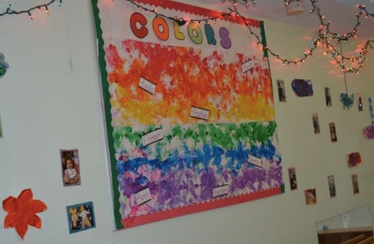 Bulletin board with "COLORS" at the top and a rainbow of painted handprints