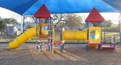 Yellow playground slide and tunnel under a blue canopy