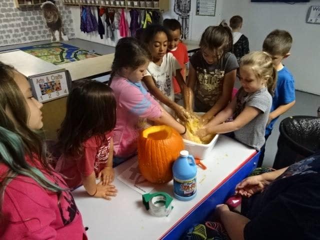 Children carving pumpkins in a classroom