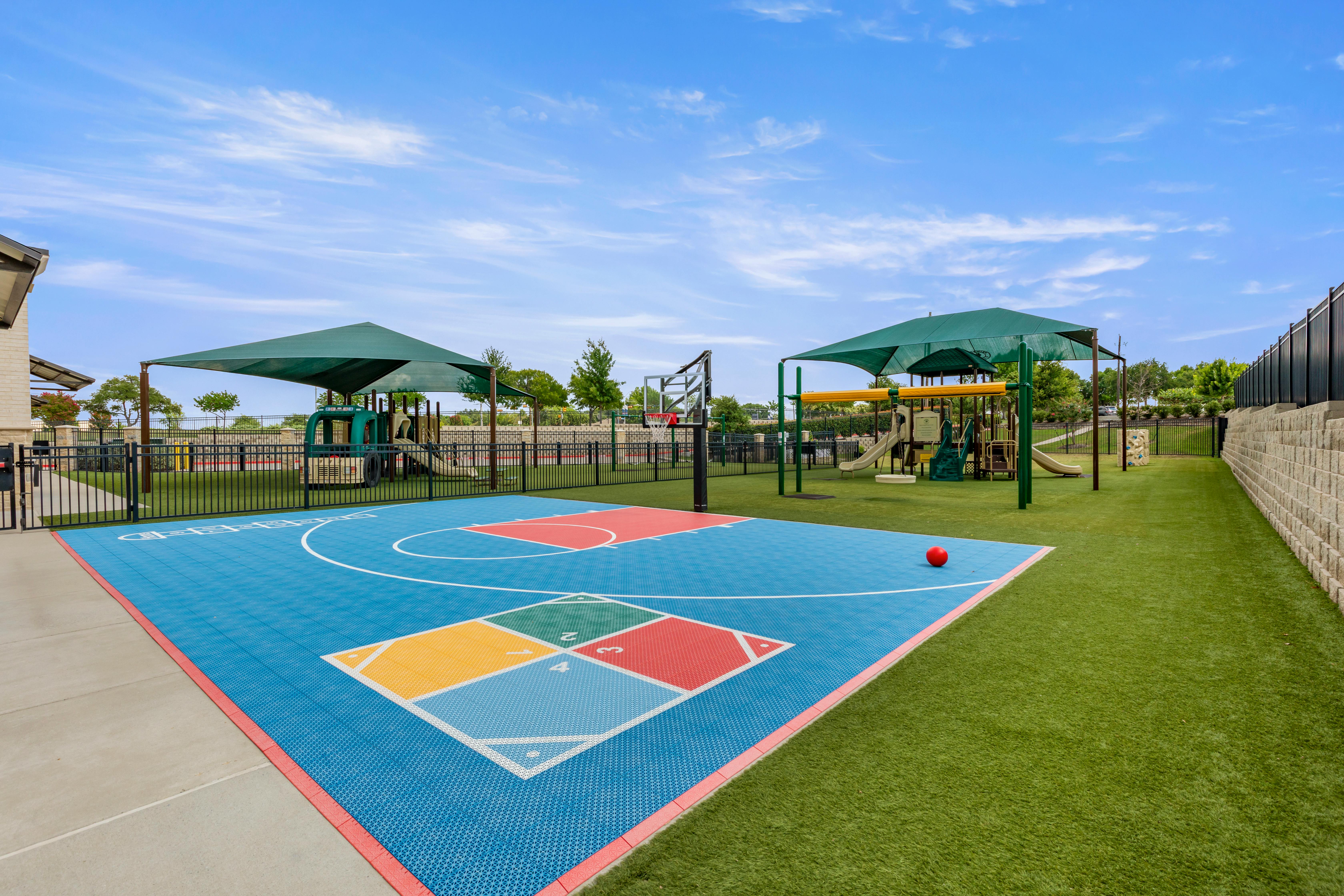 Basketball court and playground with green sunshades and artificial turf