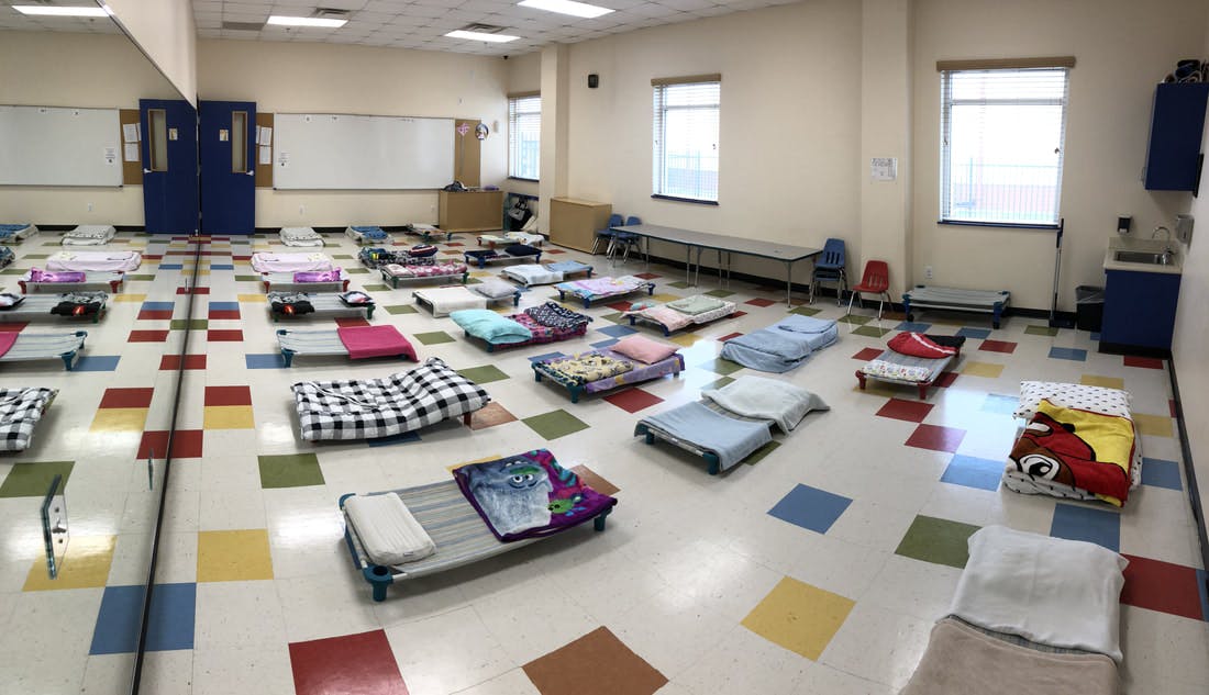 Room with many cots and sleeping mats on the floor