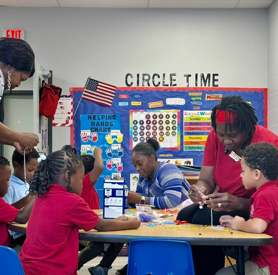 Adults and children at a table doing an activity in a classroom