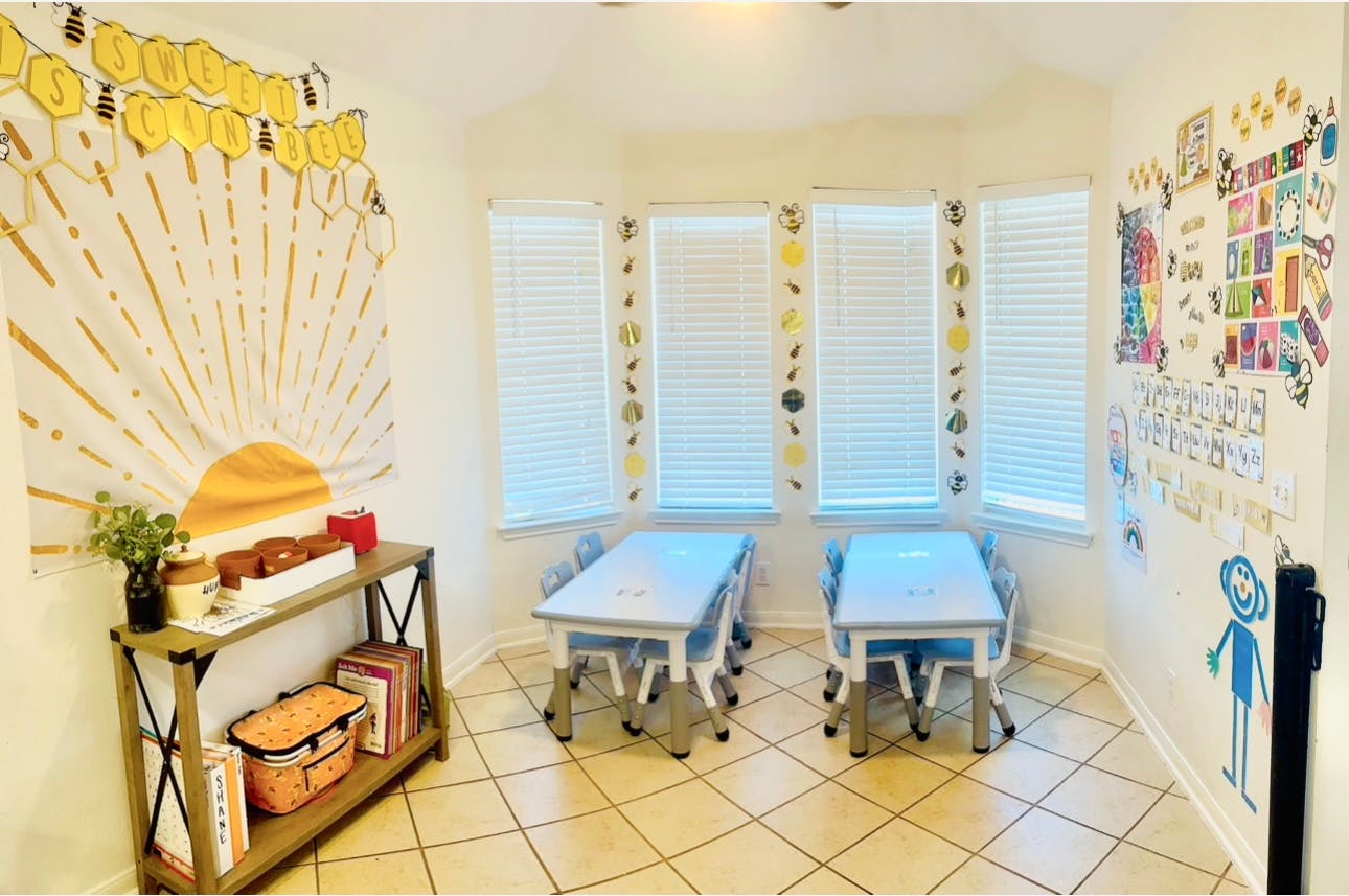 Two small tables with chairs in a room with windows and wall decorations