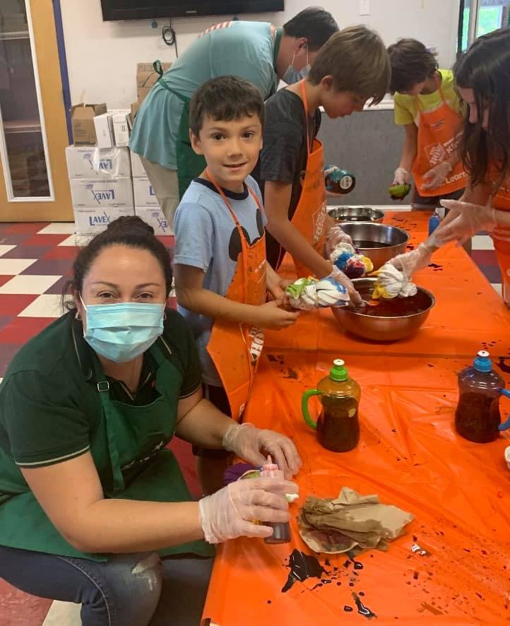 Adult and children tie-dyeing fabric at a table