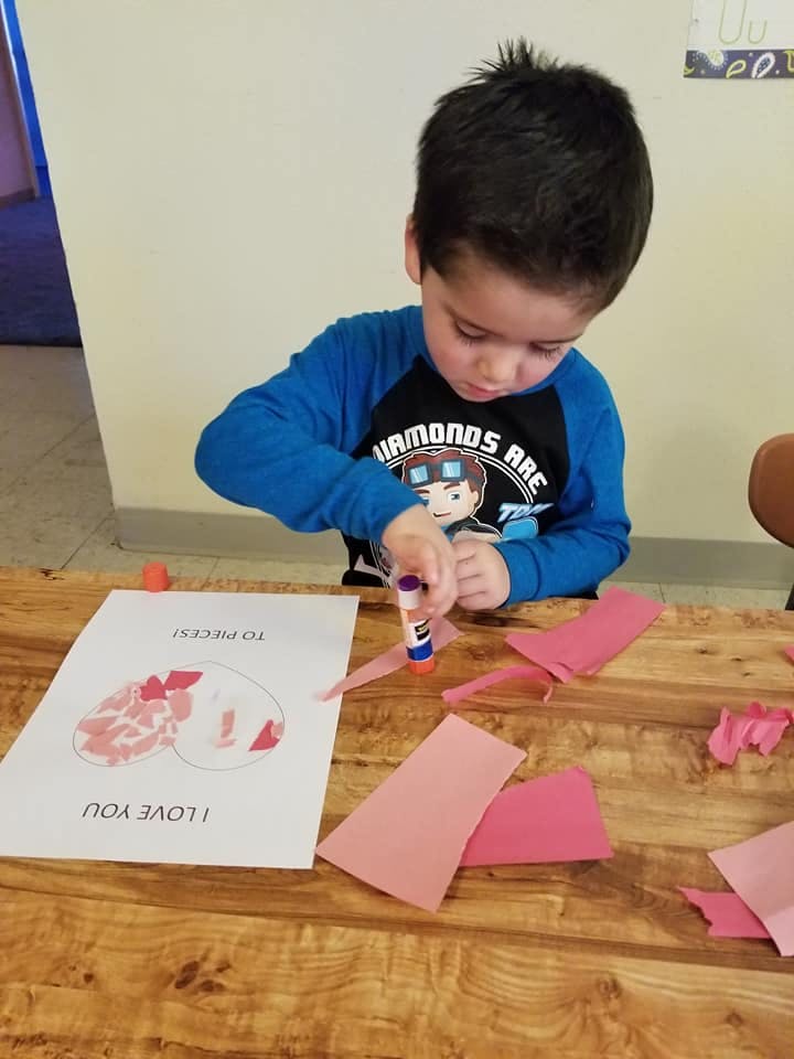 Child gluing paper onto a craft project