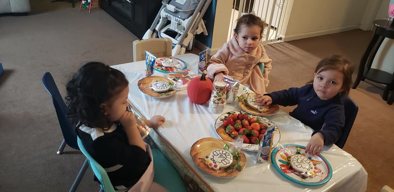 Three children sitting at a table with food