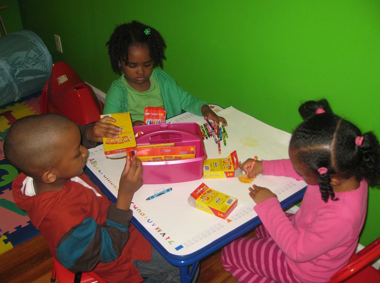 Three children drawing at a table