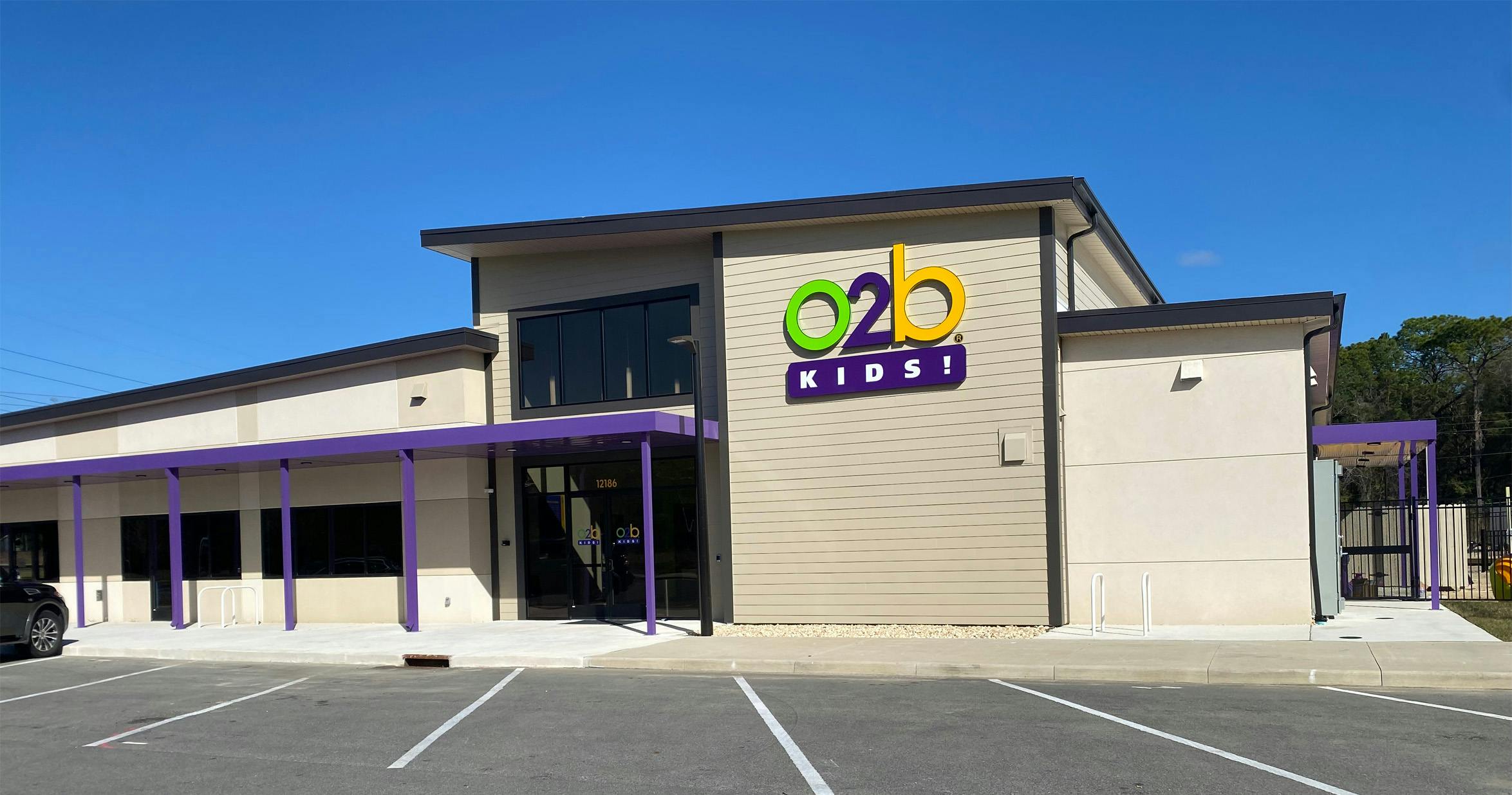 Exterior view of an "o2b Kids!" building with a parking lot in front