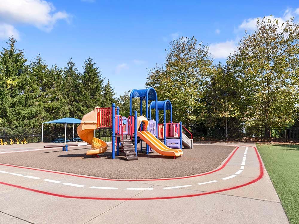 Colorful playground with slides, stairs, and a spiral tube on rubberized ground