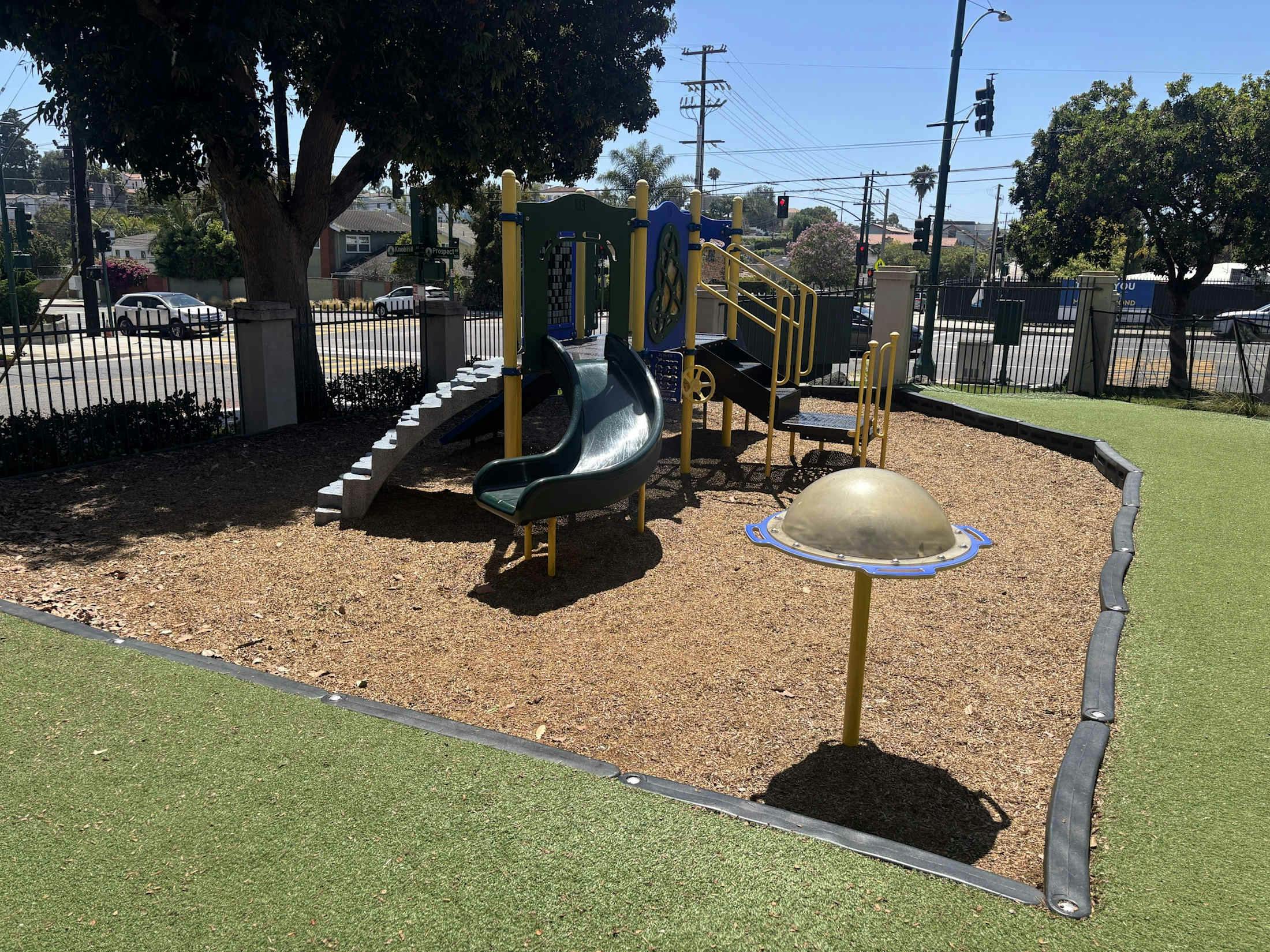 Playground equipment including a slide and a dome climber on wood chips