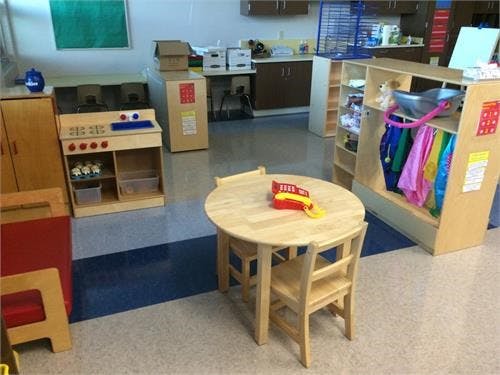 Playroom with small table and chairs, toy kitchen, and dress-up clothes rack