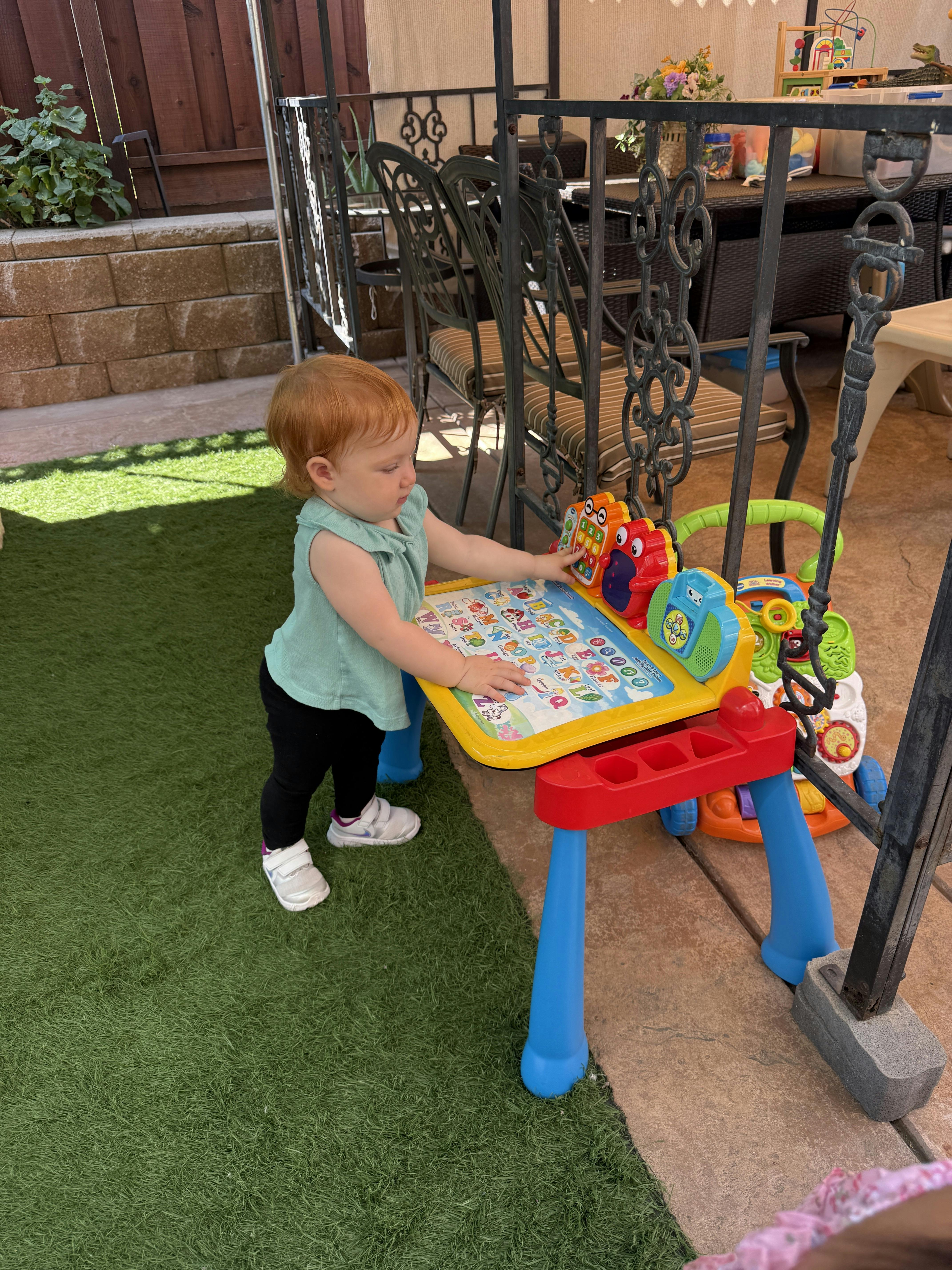 Child playing with an activity table on artificial grass