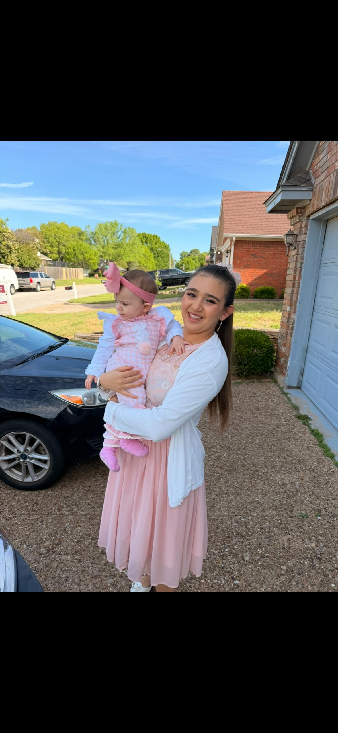 Person holding a child with a pink bow on their head
